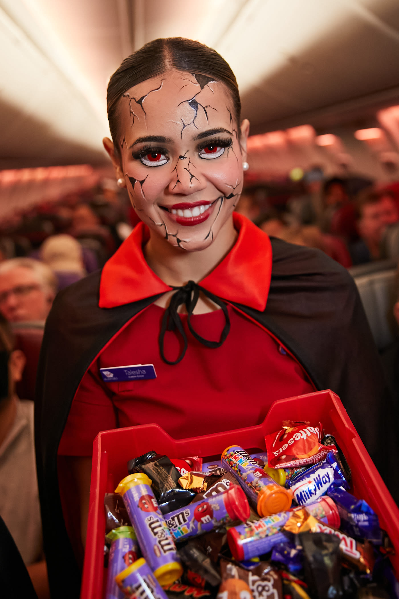 Virgin Australia cabin crew in Halloween fancy dress holding a tray of Mars Wrigley treats, stood in the aisle of a Virgin Australia plane