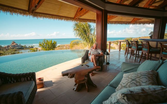 Richard Branson sitting by the pool on Necker Island, reading