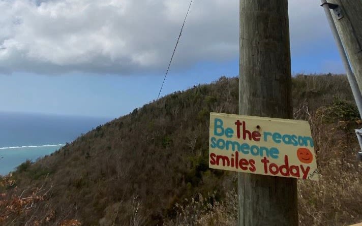 A sign saying be the reason someone smiles today