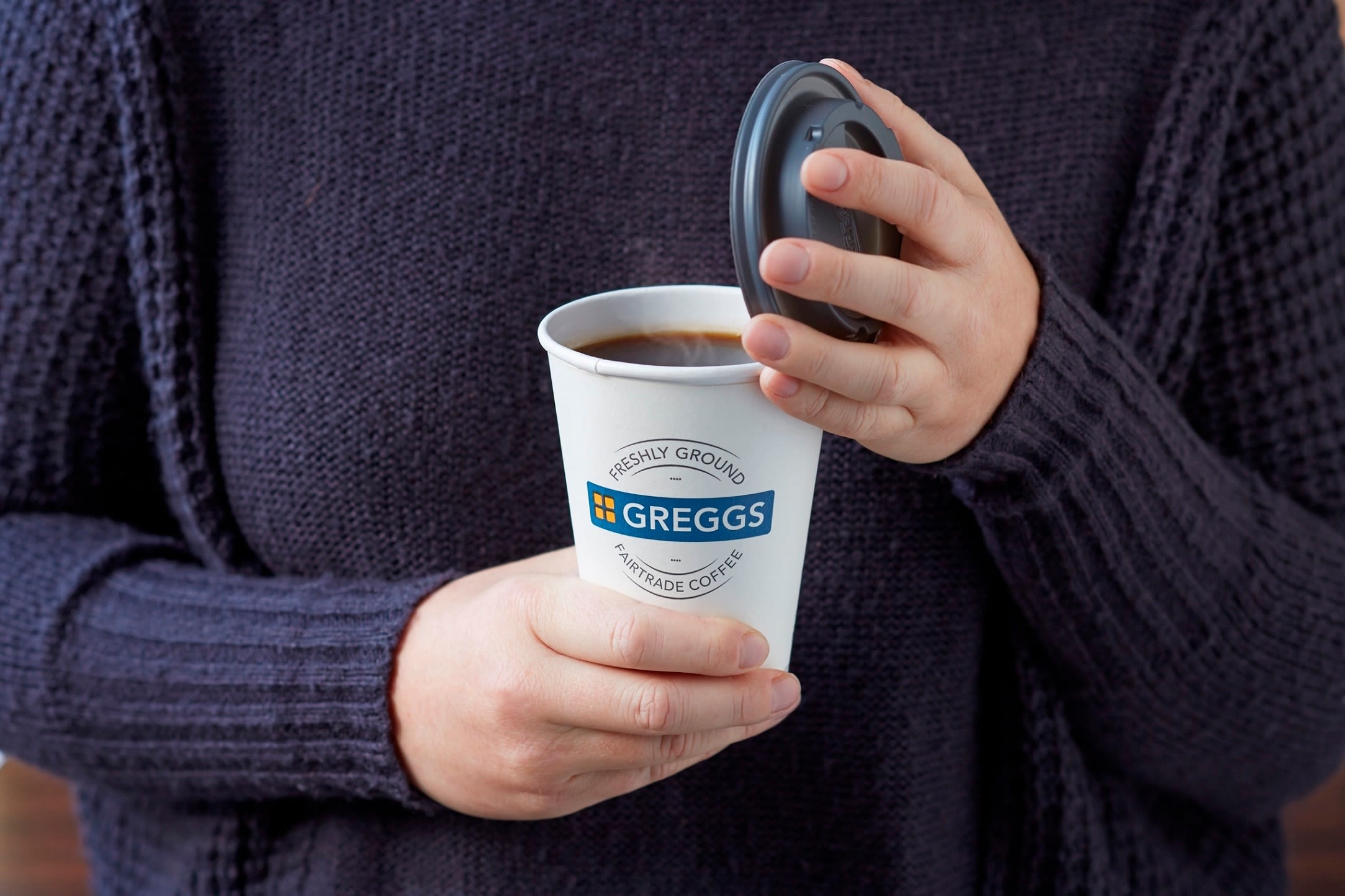 Person holding a Greggs hot drink