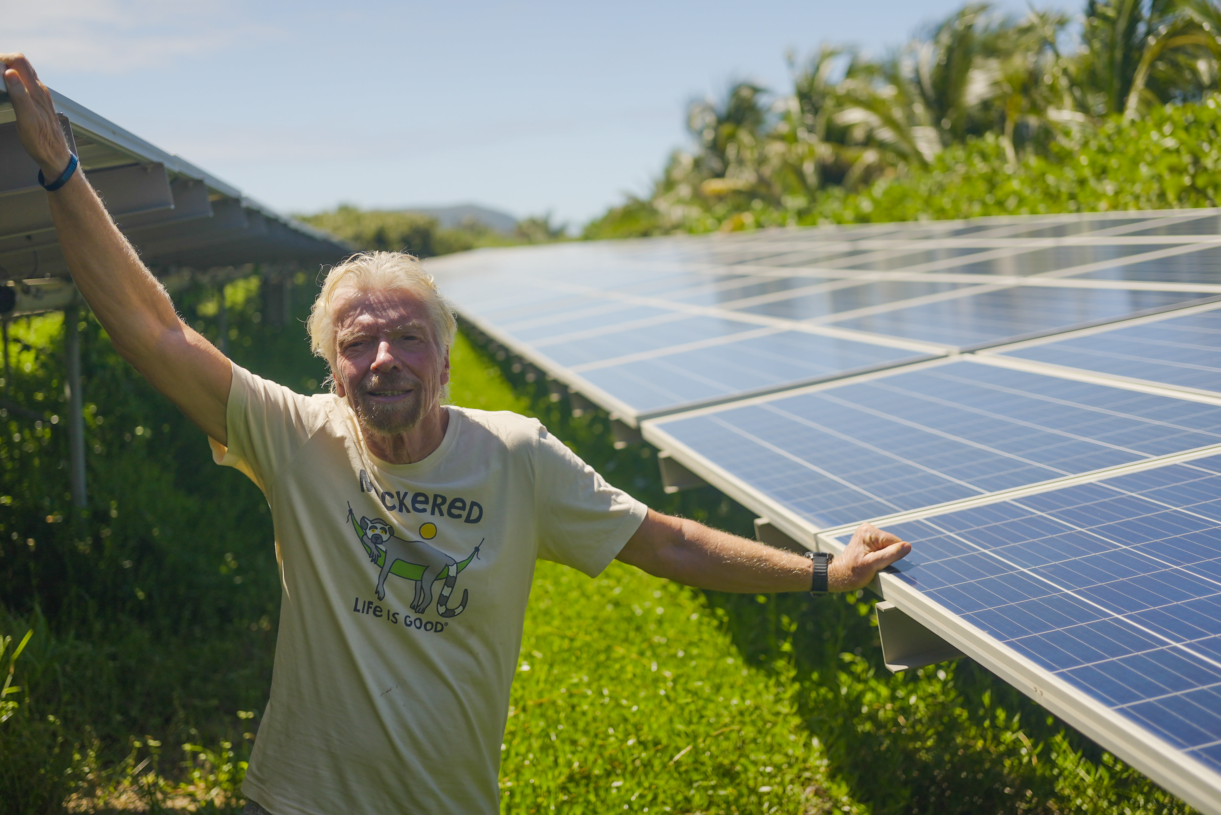 Richard Branson standing in front of the solar panels on Necker Island 