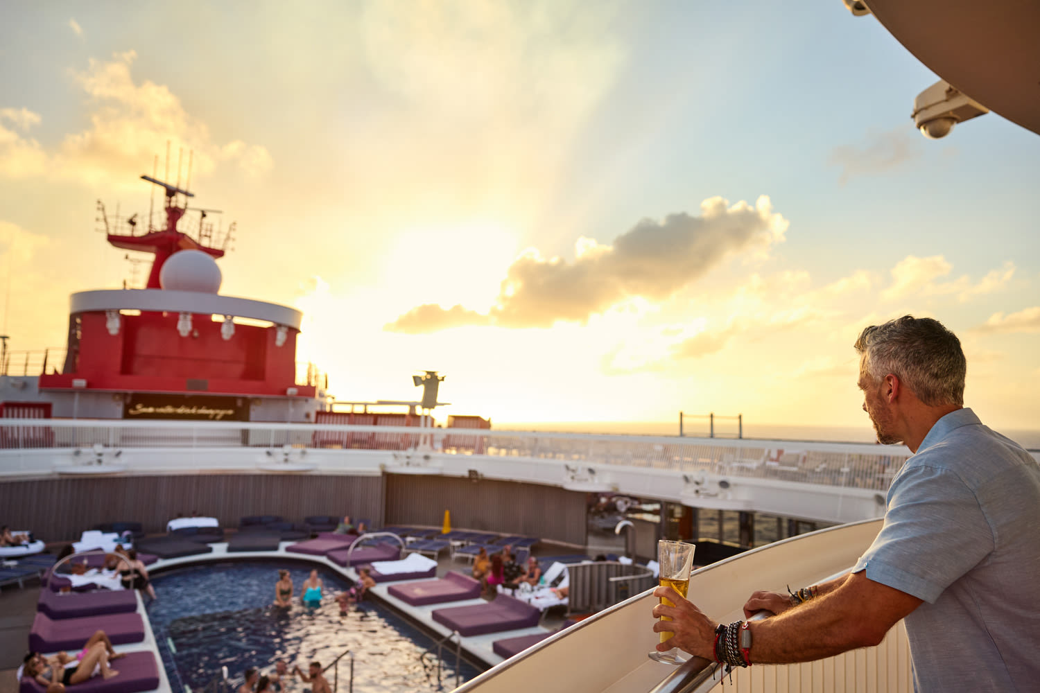 A man looking down at the swimming pool deck on Virgin Voyages