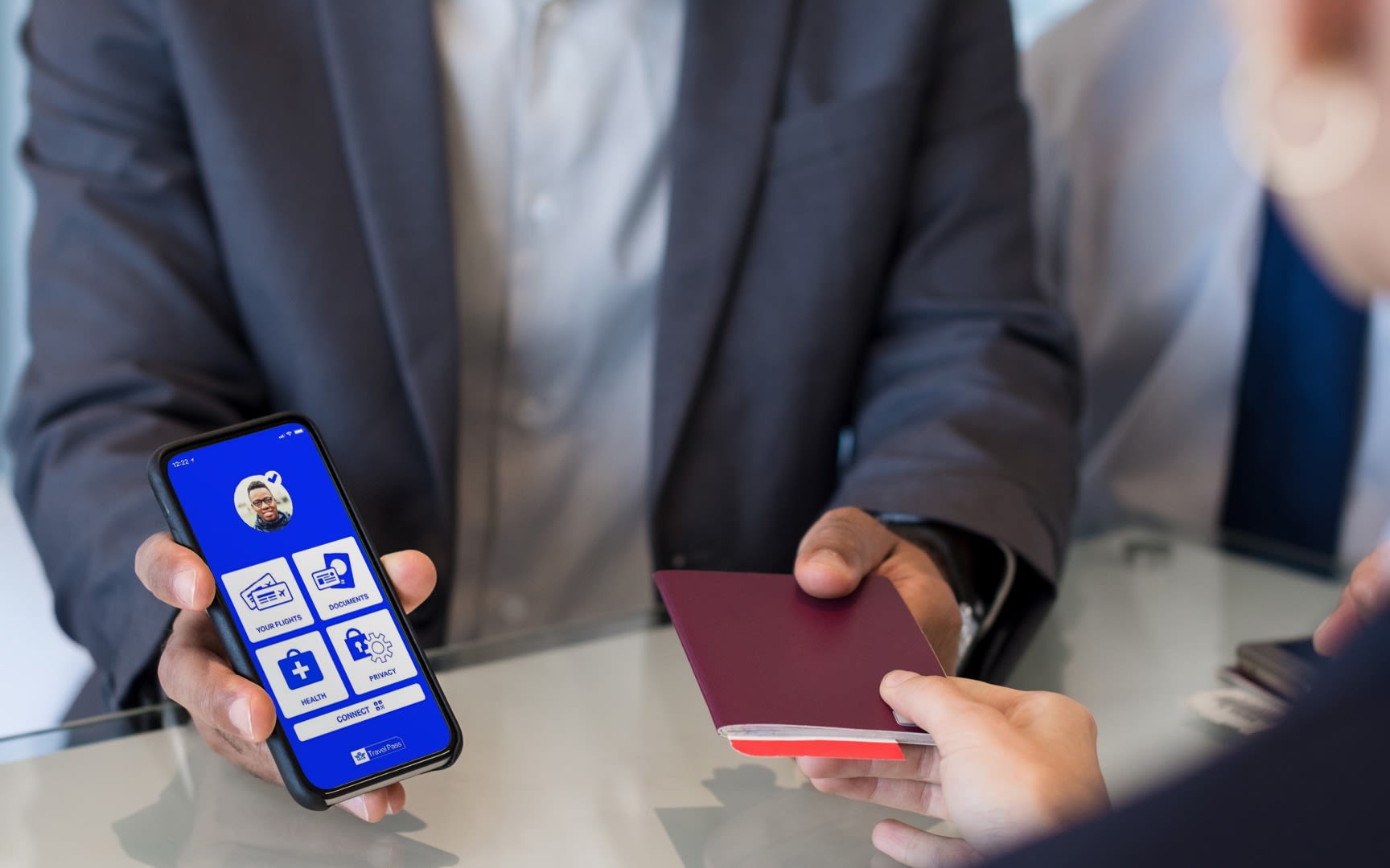 A man shows his IATA Travel Pass app to an airline worker and hands over his passport