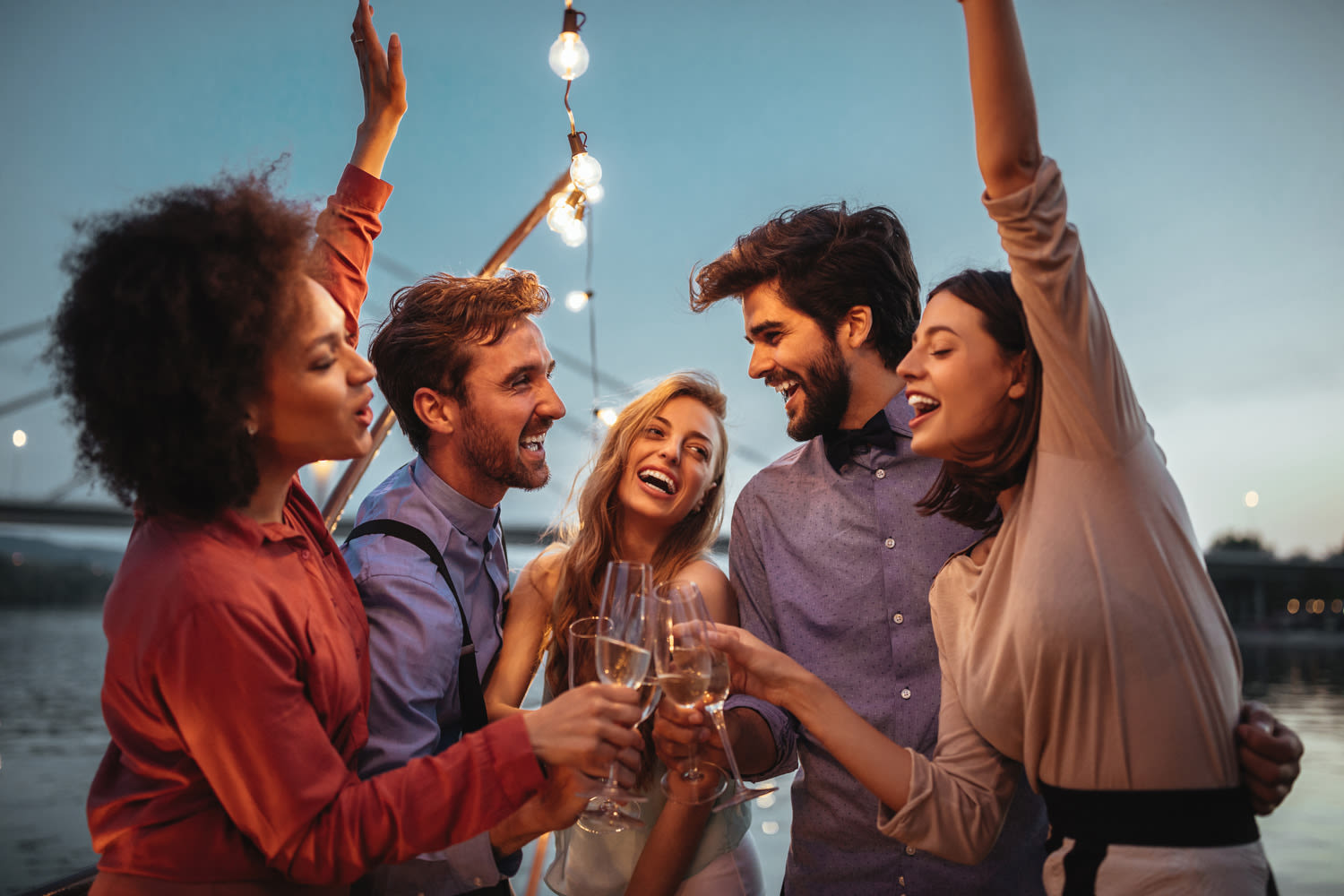 A group of five friends raising a toast on a summer's evening