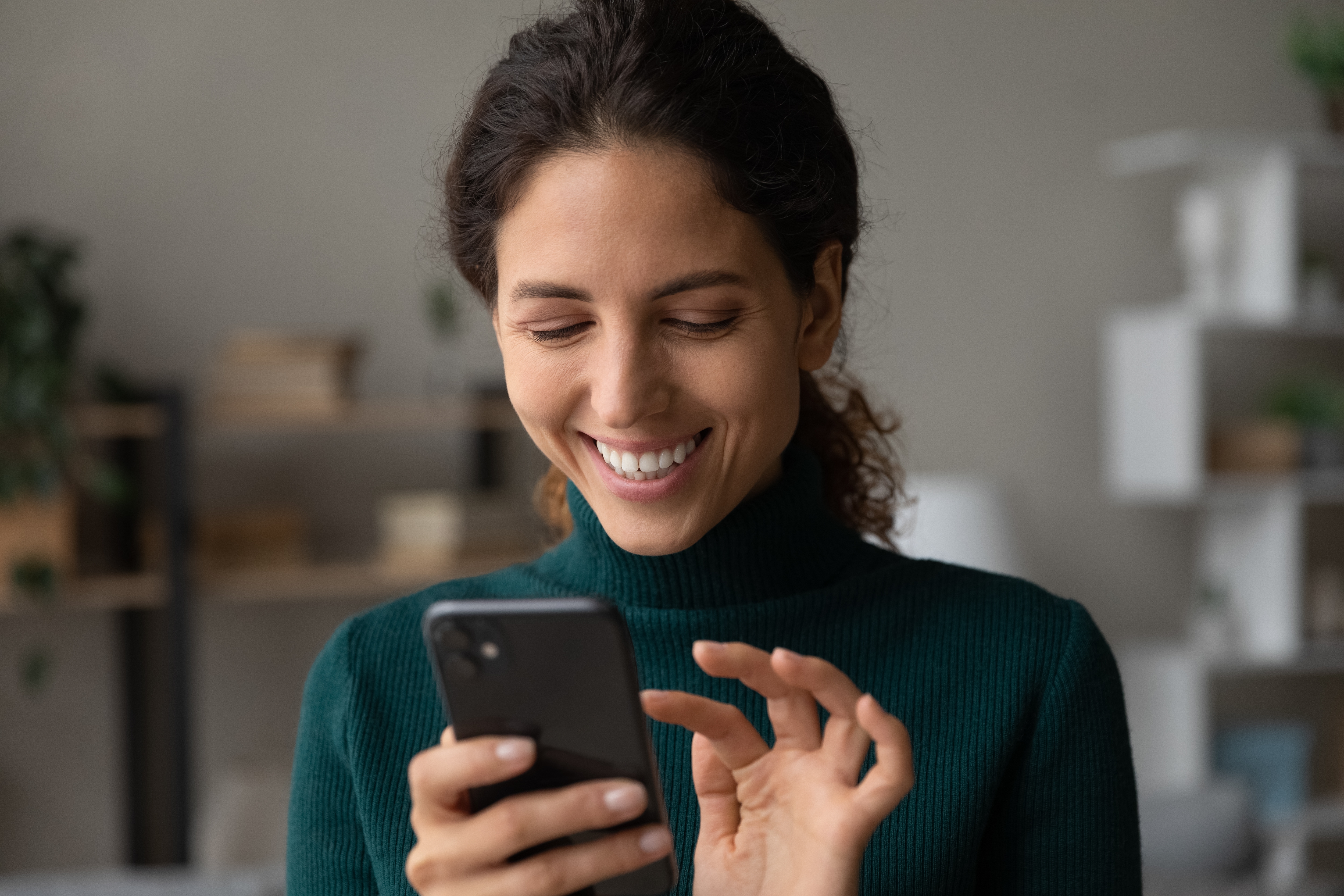 Image of smiling millennial latina lady touching her smartphone.
