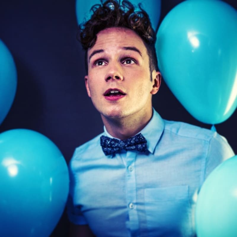 Author Olly Pike surrounded by blue balloons