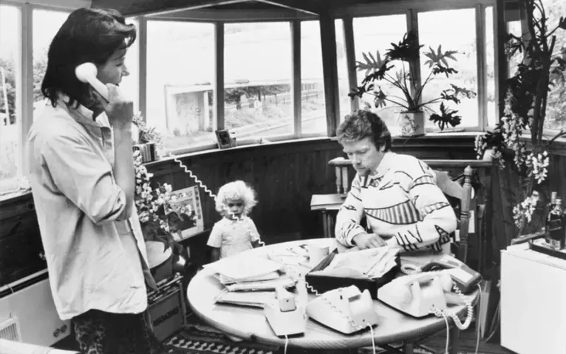 Holly Branson as a toddler with her mum and dad and several phones on the table