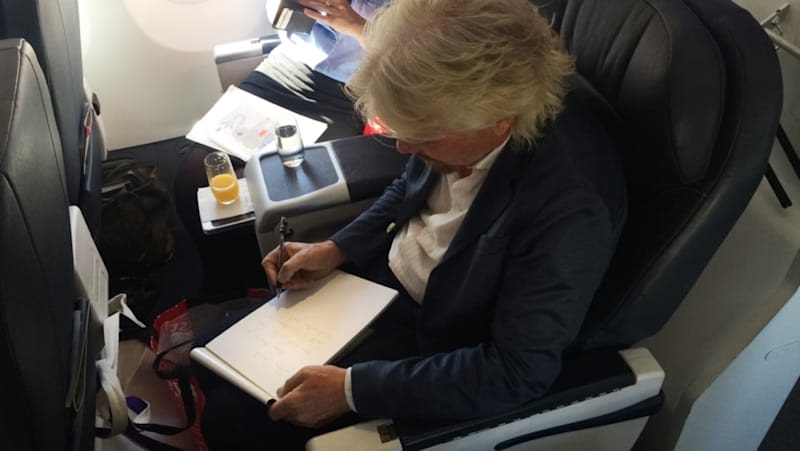 Richard Branson sitting on a plane, writing