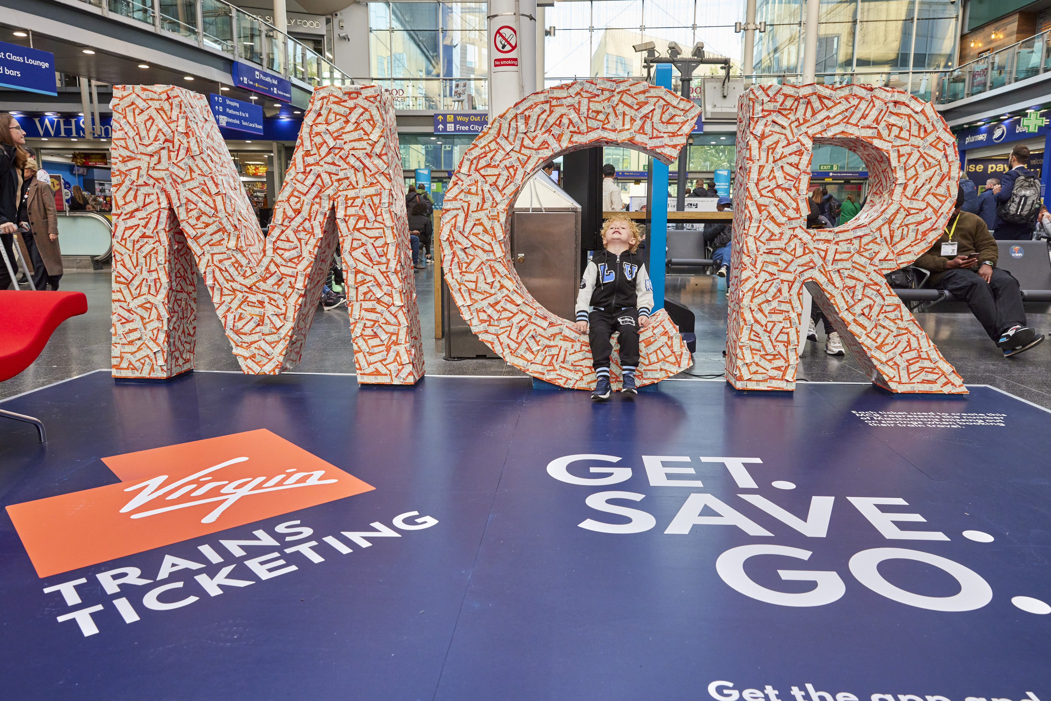Child standing in front of Virgin Trains Ticketing pop up in Manchester Piccadilly Station