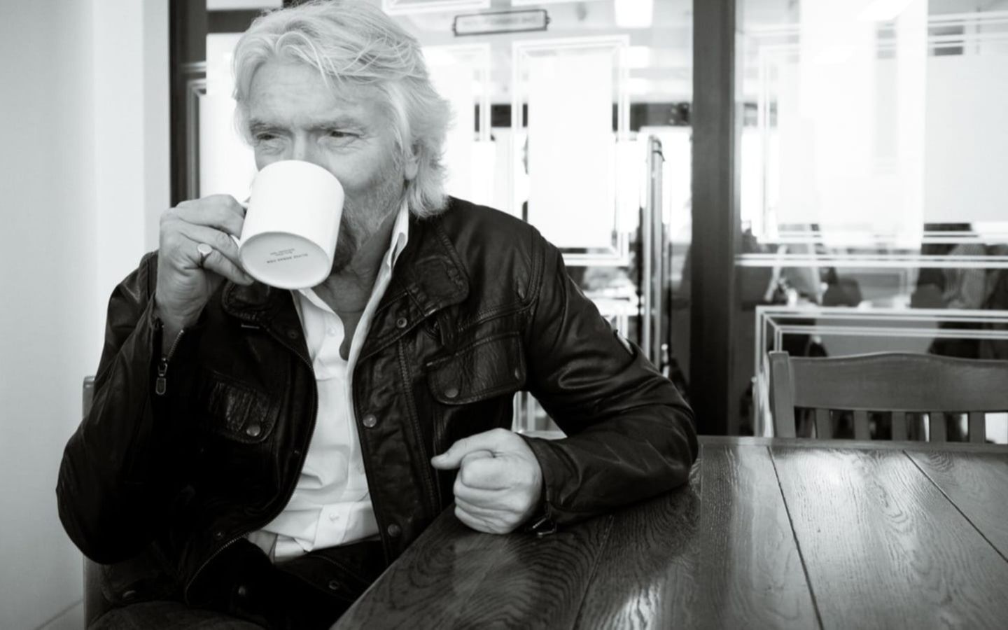 Black and white photo of Richard Branson in the office drinking tea