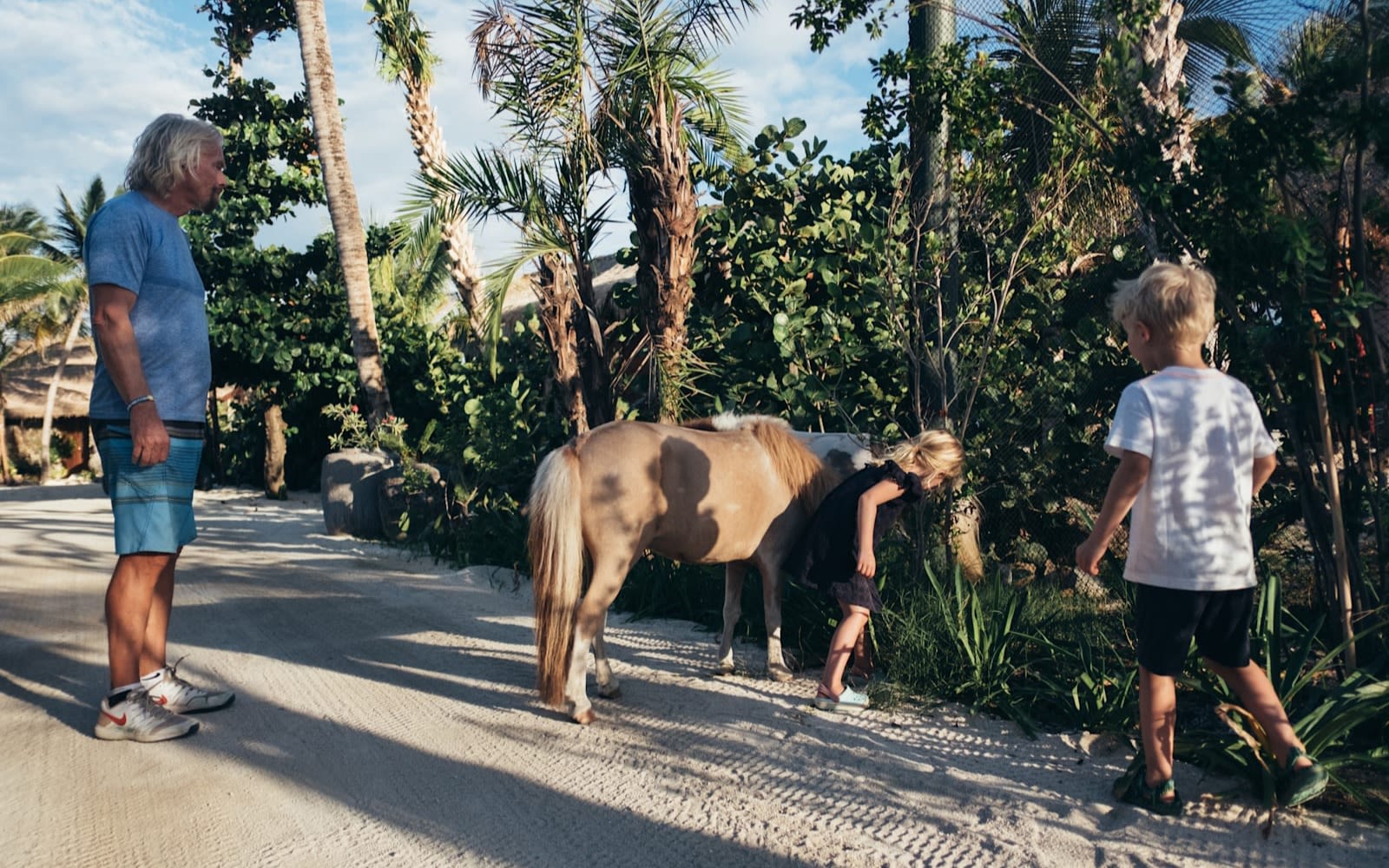 Richard Branson and his grandchildren walking with a miniature horse