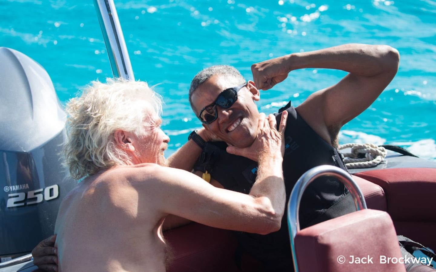 Richard Branson and Barack Obama on a boat, smiling and joking