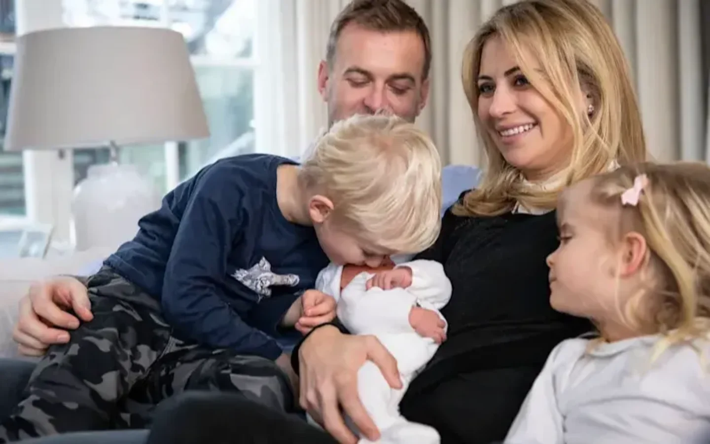 Holly Branson sitting down holding newborn baby Lola, surrounded by her husband Freddie and twins Artie and Etta
