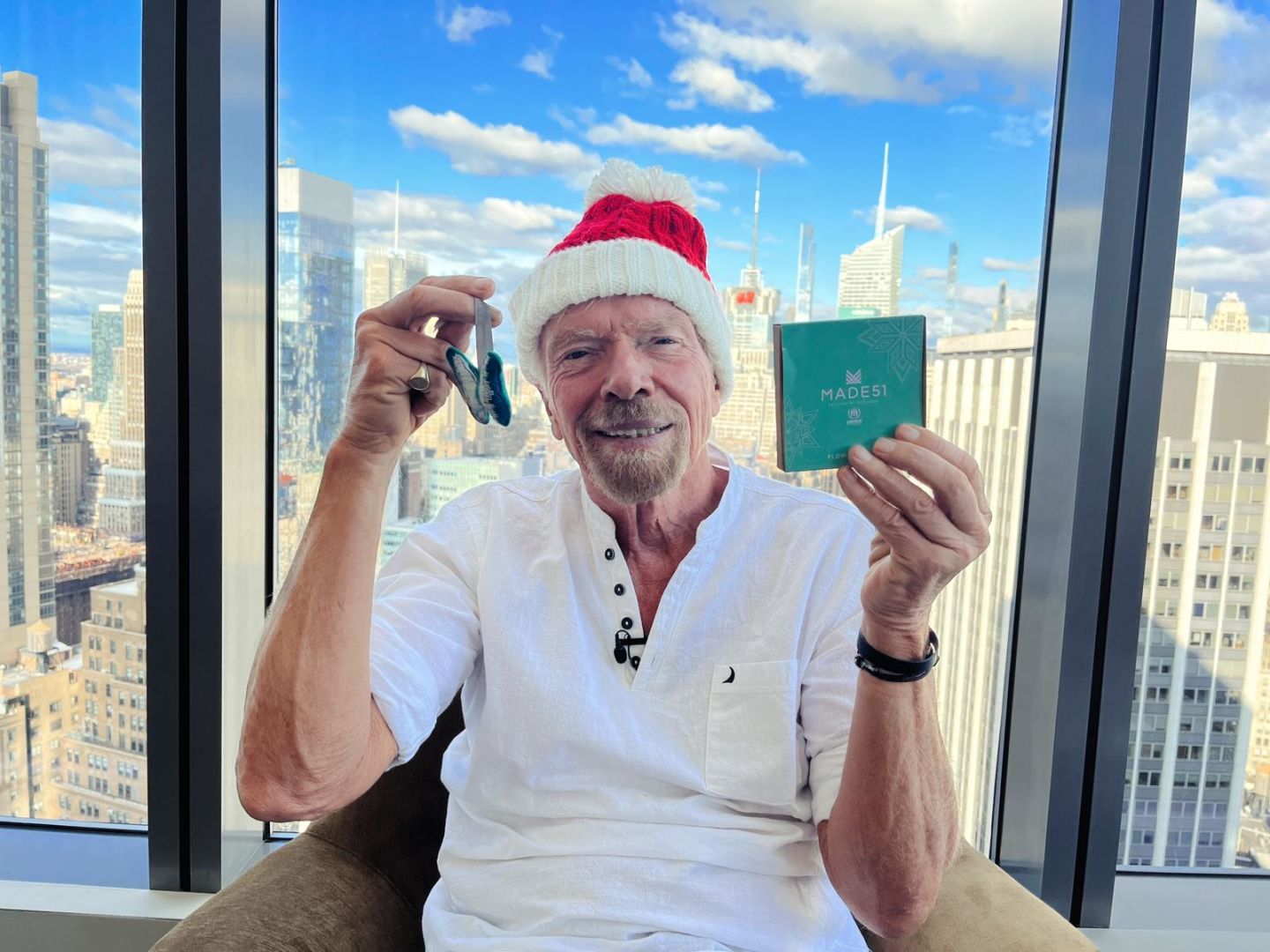 Richard Branson holding up Made51 Christmas ornaments made by refugees