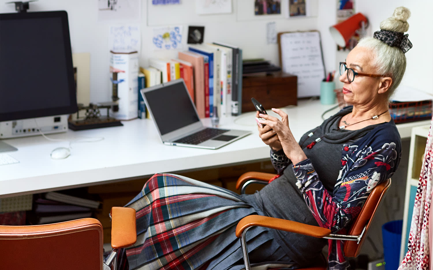 A woman sitting in her home office using her phone