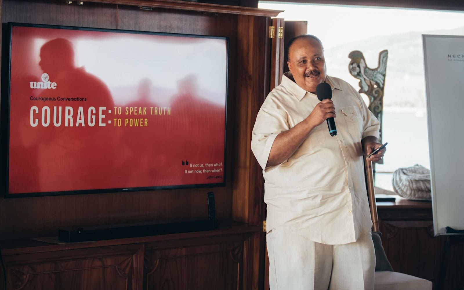 Martin Luther King III speaking at a Virgin Unite event on Necker Island wearing a cream shortsleeve shirt and trousers