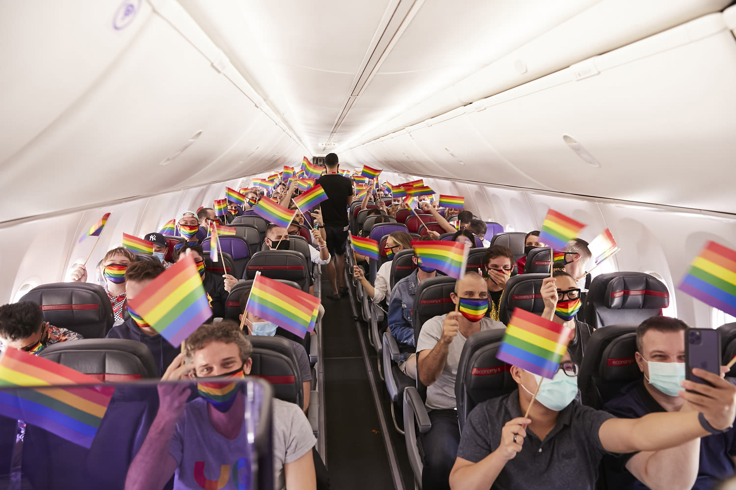Guests waving rainbow flags on a Virgin Australia Pride Flight
