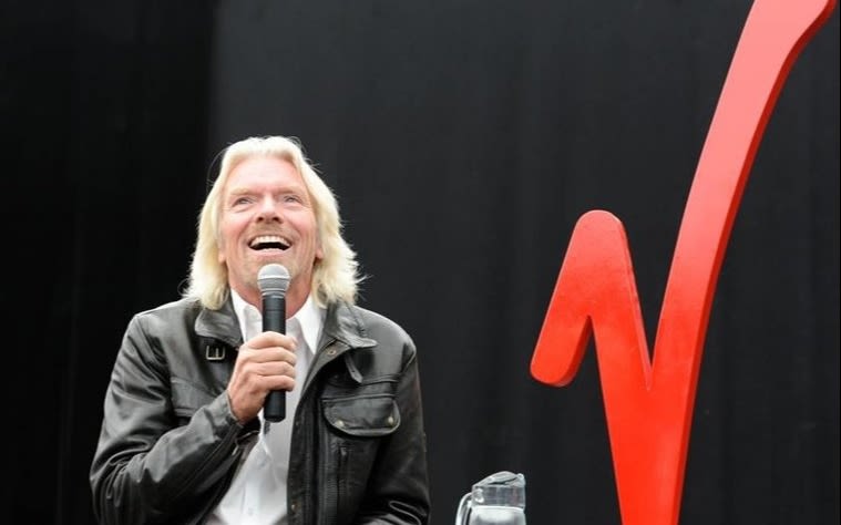 Richard Branson holding a microphone and smiling