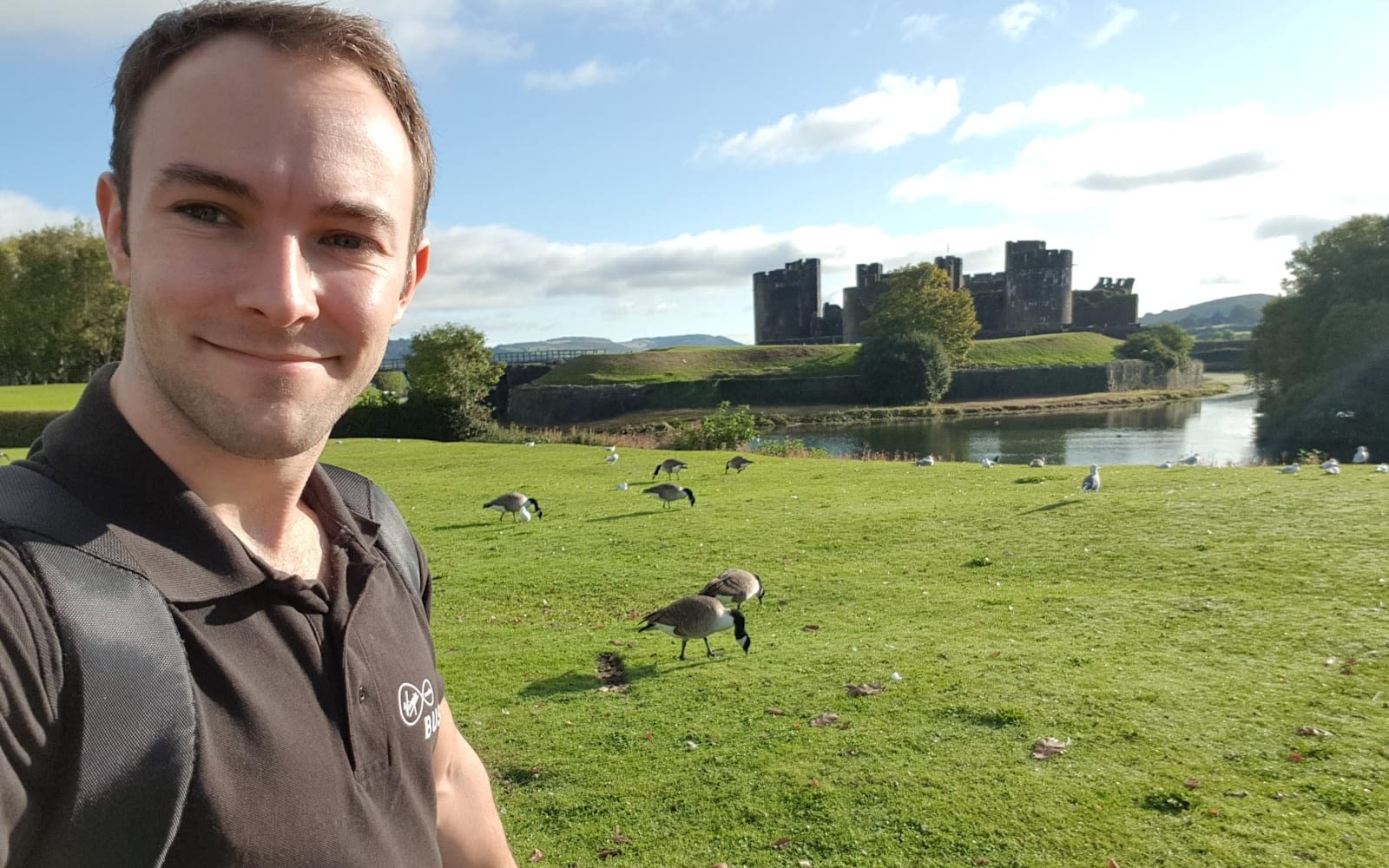 Lewis stands by a castle moat.