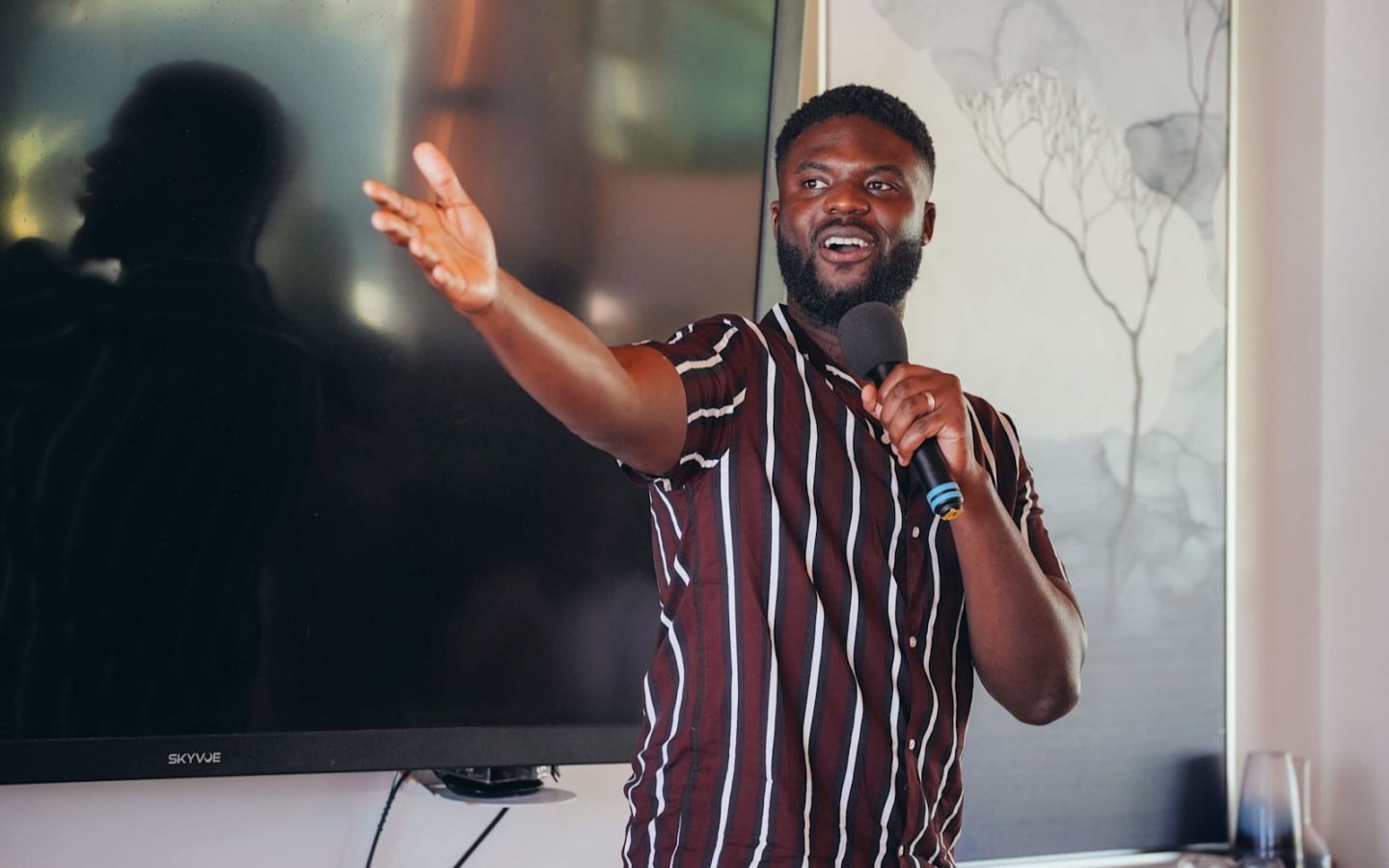 Karl Loko giving a speech wearing a stripey shirt