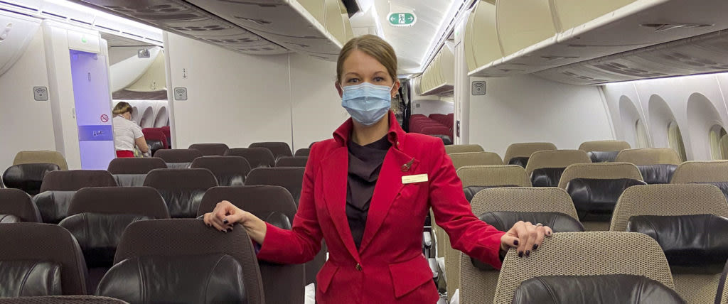 A member of Virgin Atlantic cabin crew wears a mask while standing in Premium Economy on a Virgin Atlantic plane