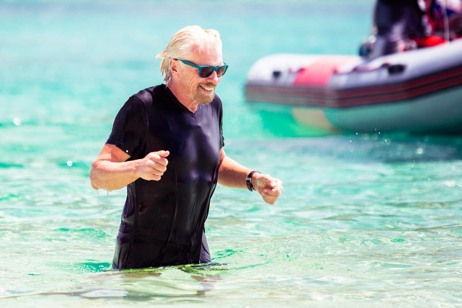 Richard Branson in the ocean, walking to shore, smiling