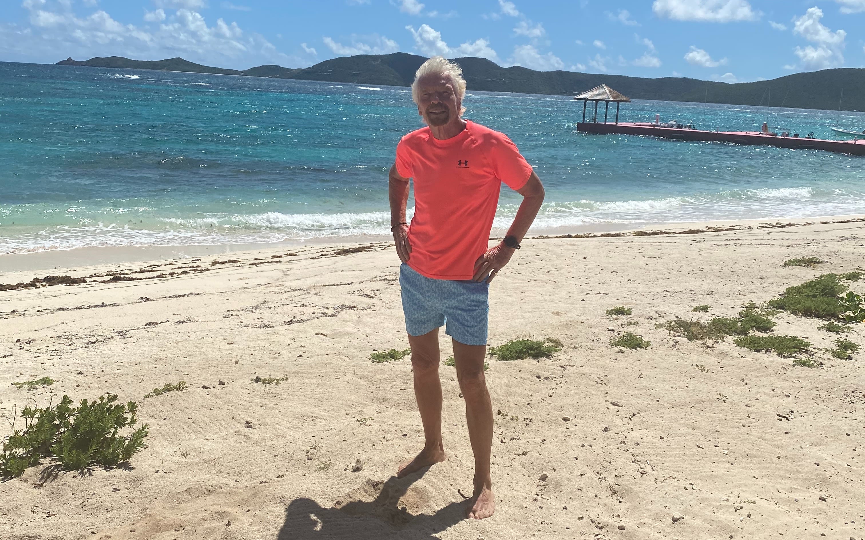 Richard Branson standing on the beach about to go for a swim 