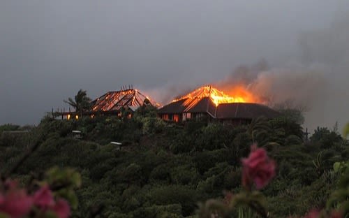View from a distance of a fire burning through a house