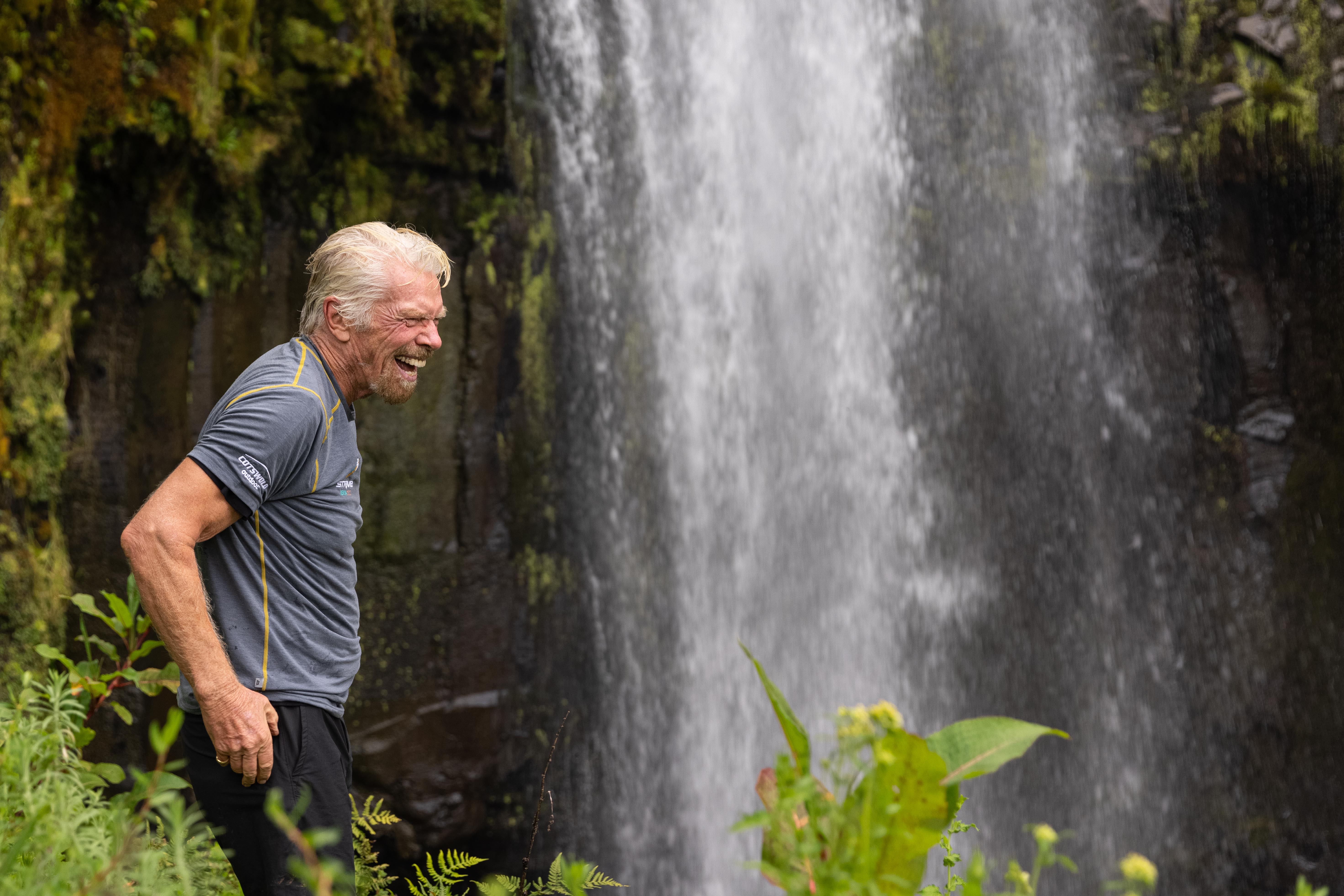 Richard Branson smiling near a waterfall