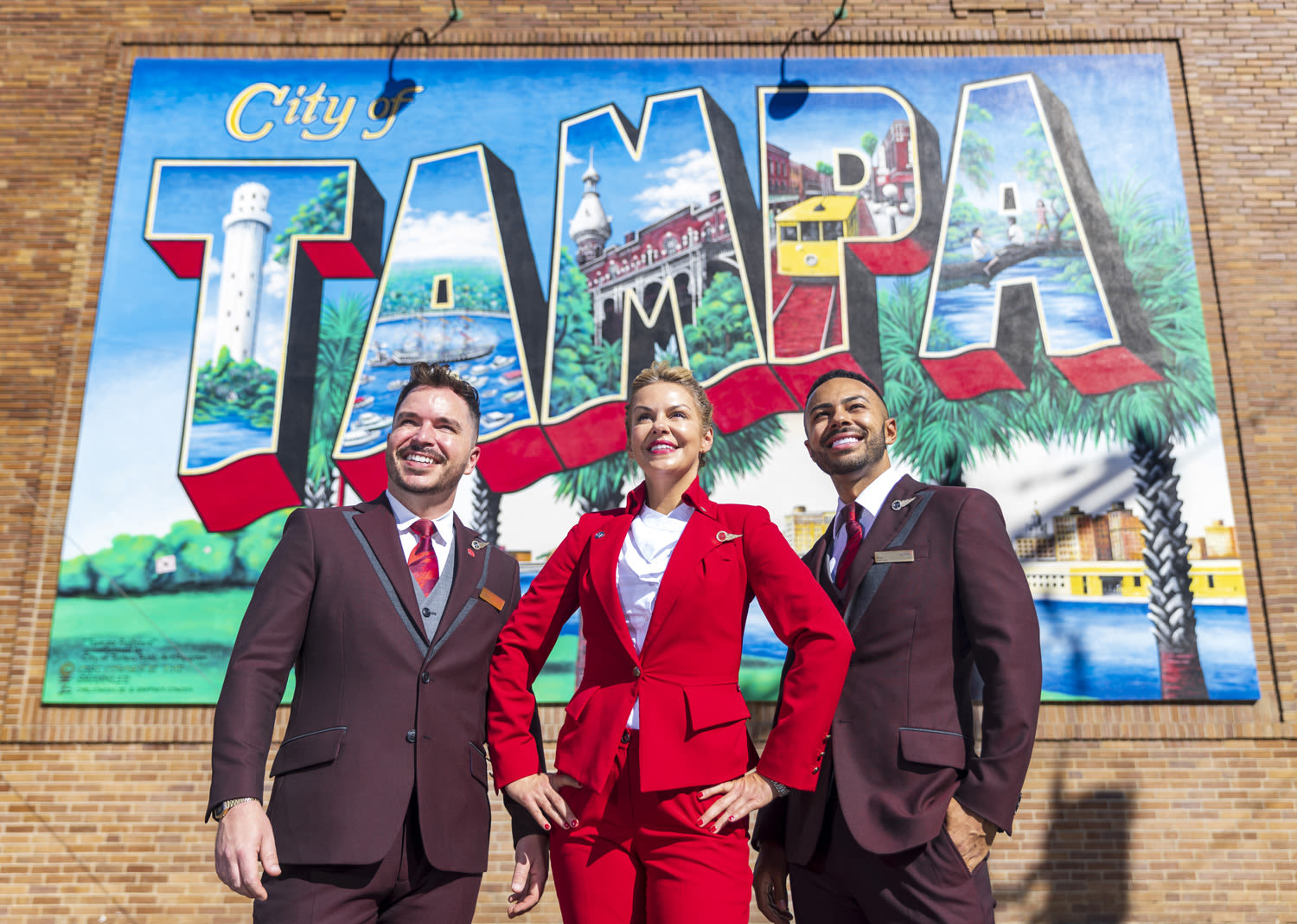 Three Virgin Atlantic flight attendants in front of a Tampa mural