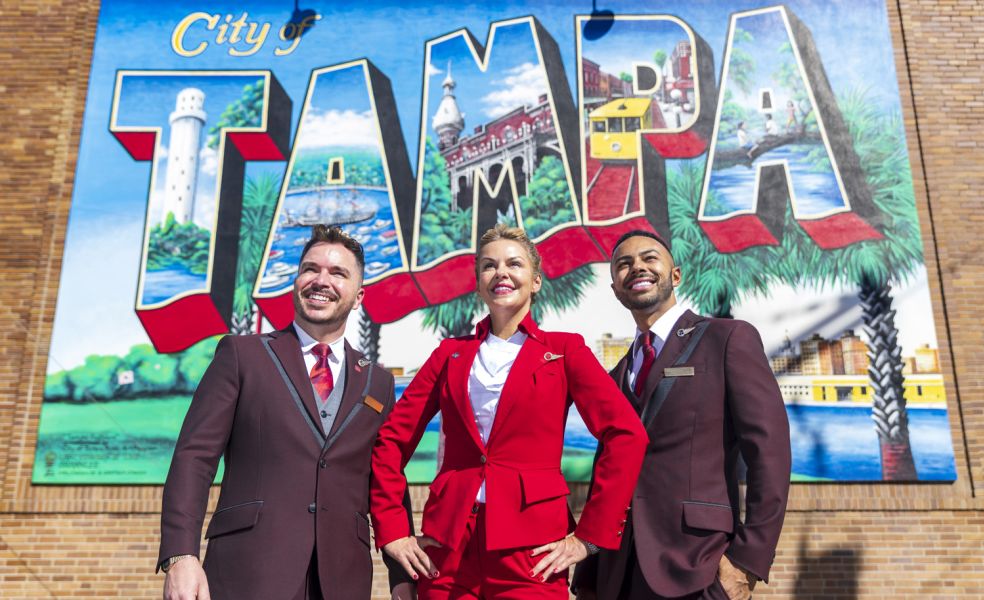 Three members of Virgin Atlantic cabin crew stood in front of a Tampa mural