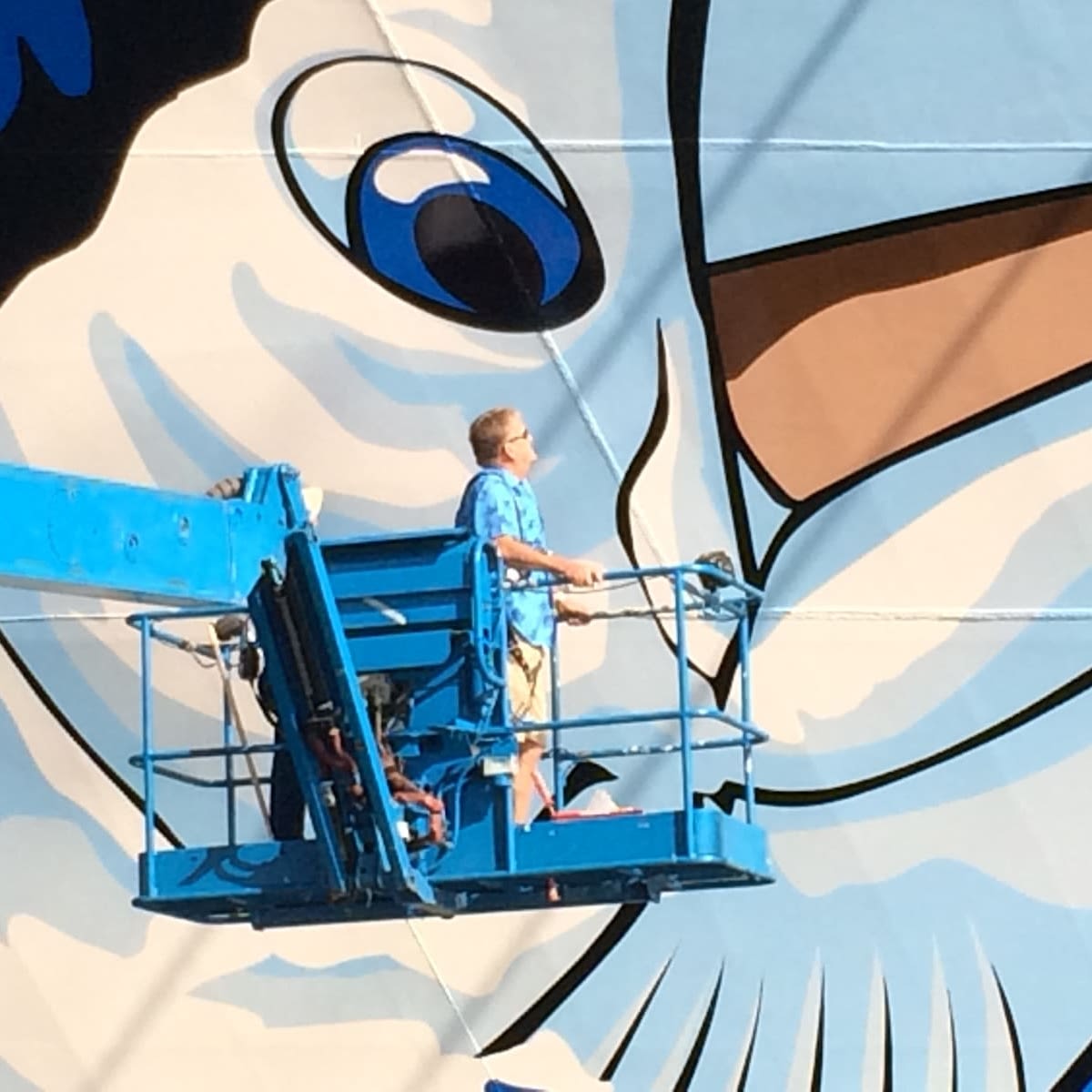 Fred Garth, up in a crane, at the side of a large mural
