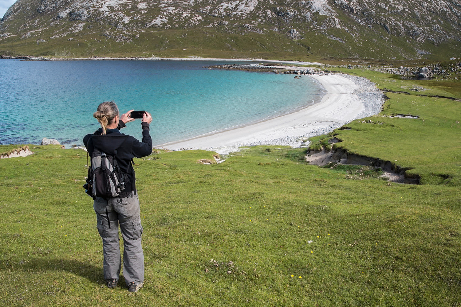 A hiker takes a picture with a phone of a beautiful beach in the Outer Hebrides in Scotland