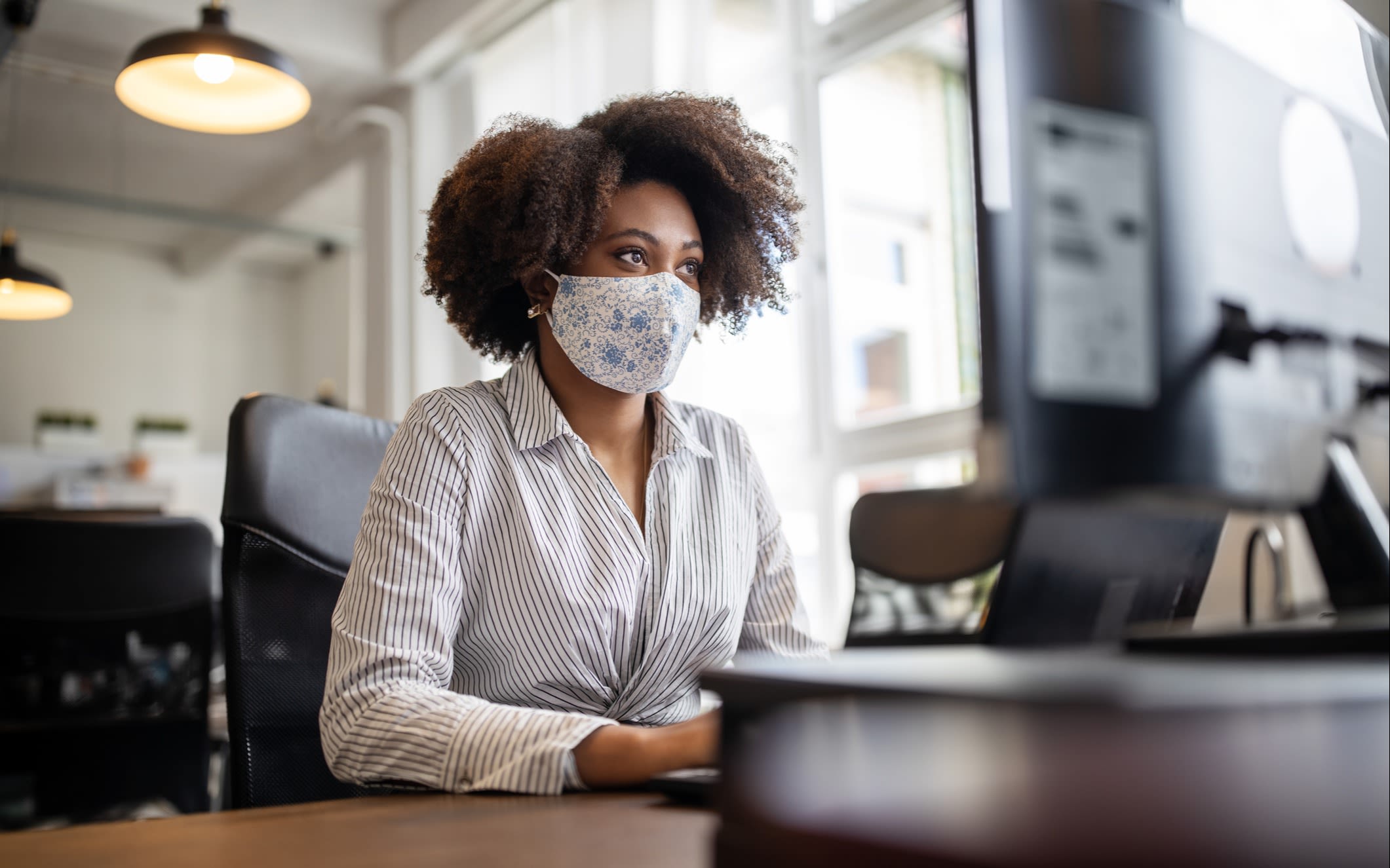 A woman wears a face mask while in her office