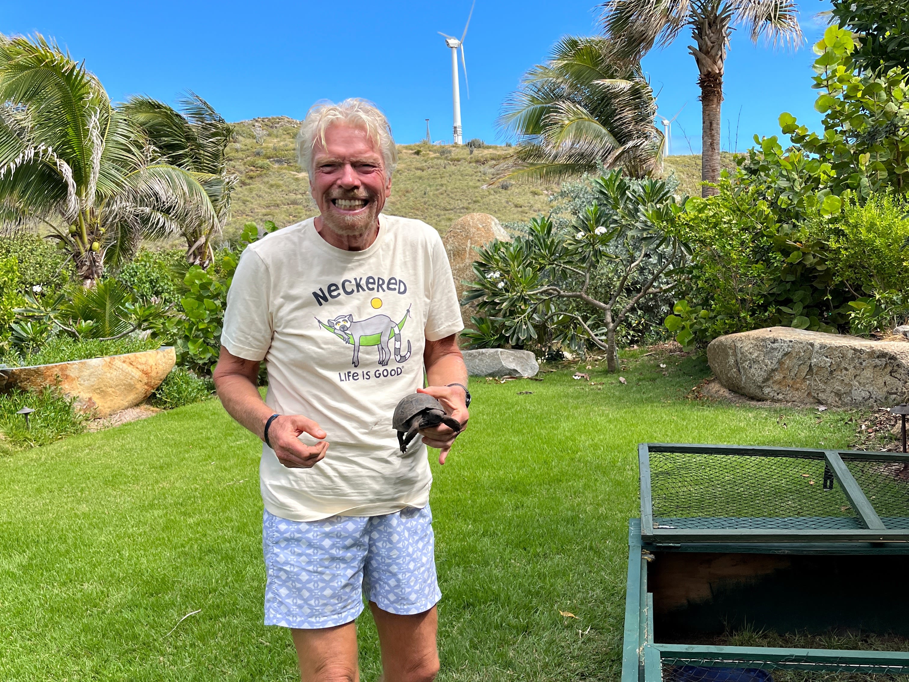 Richard Branson smiling and holding a baby tortoise on Necker Island