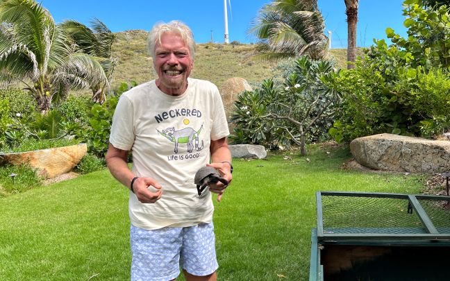 Richard Branson smiling and holding a baby tortoise on Necker Island