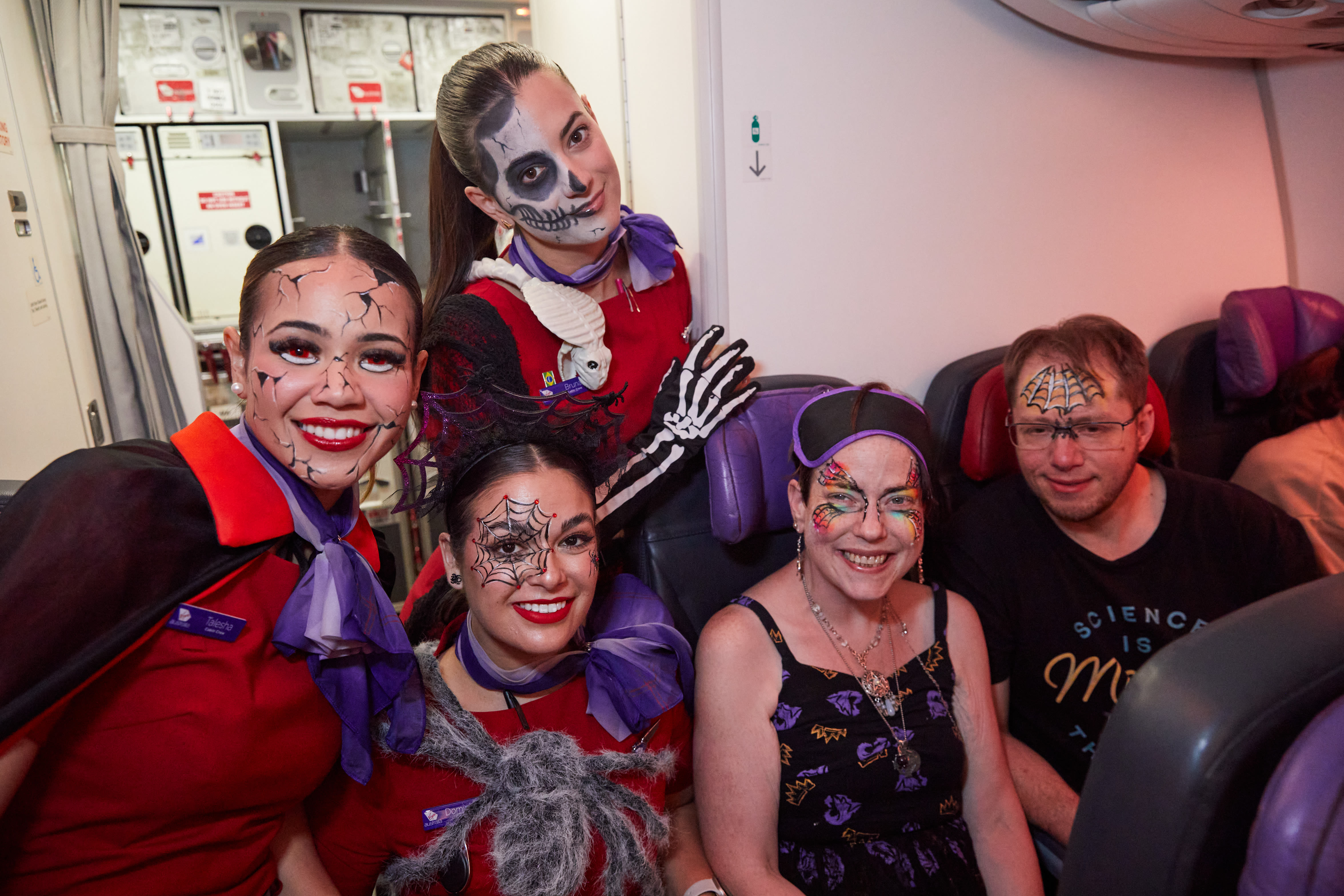 Three Virgin Australia cabin crew with two passengers, all in Halloween fancy dress costumes