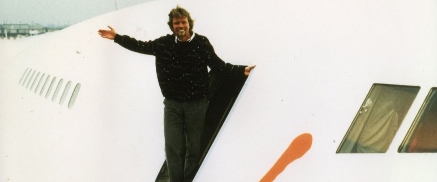 Richard standing  at the entrance of a plane smiling 