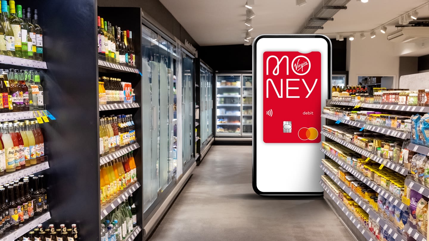 A supermarket aisle with an oversized smartphone showing a Virgin Money debit card