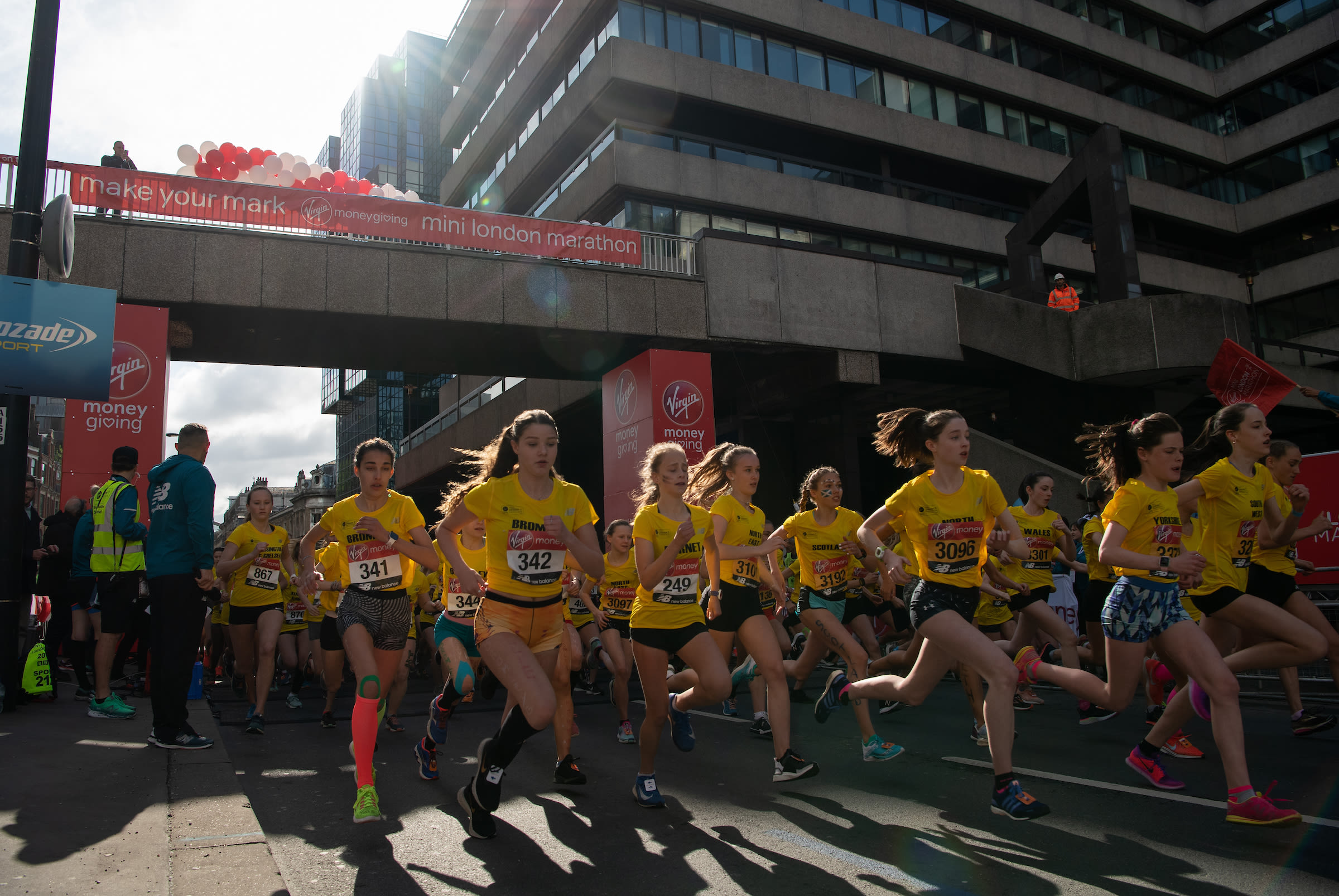 School children wearing yellow t-shirts run in the Virgin Money Giving Mini London Marathon 2019