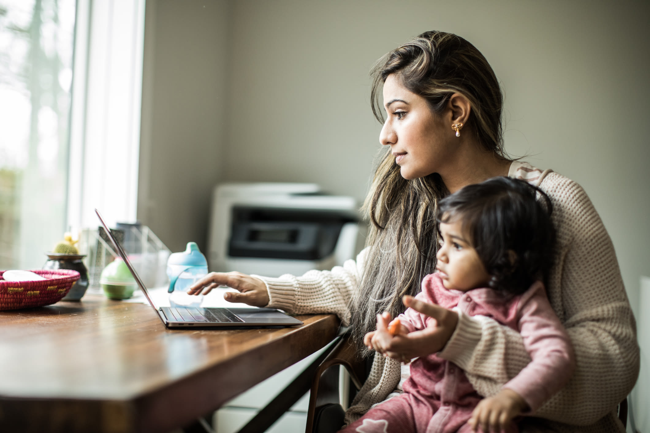 A woman working on her laptop with a child on her lap