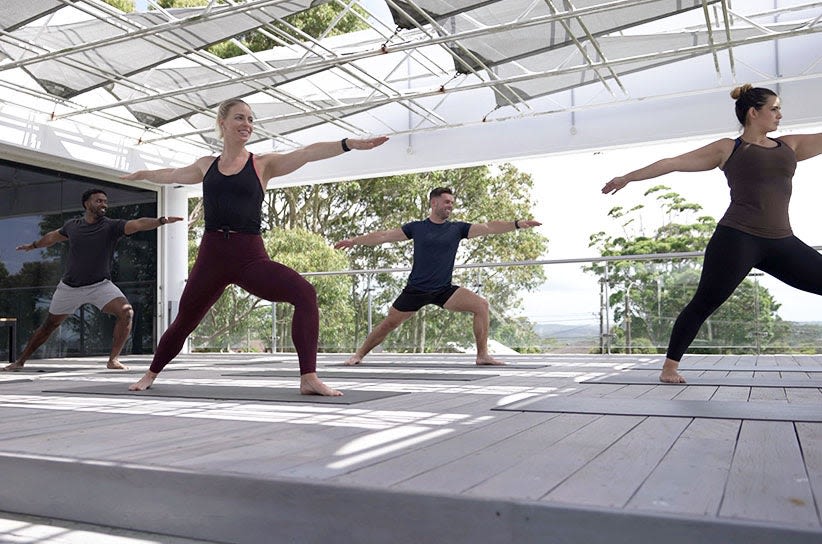 Four people practising yoga outside