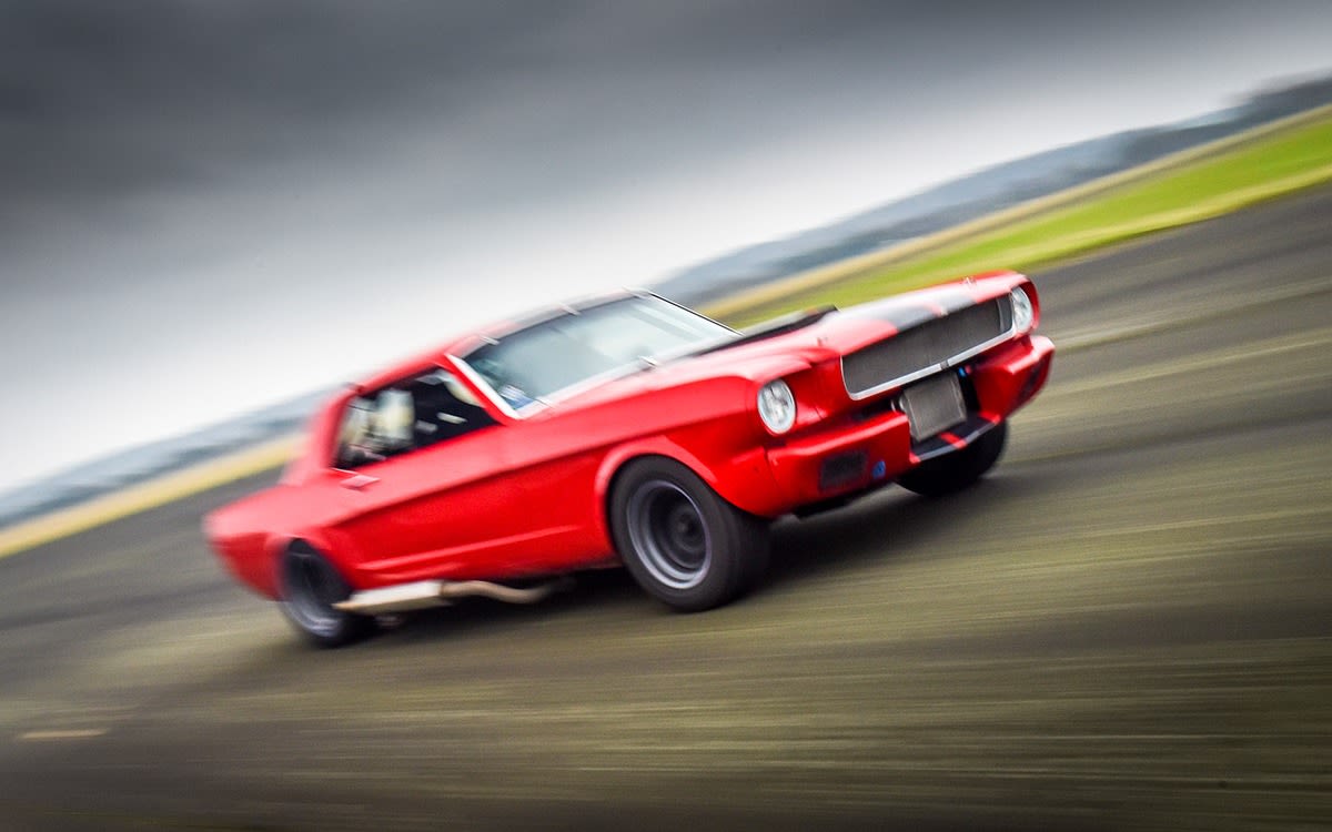 Image of a red mustang travelling at high speed.