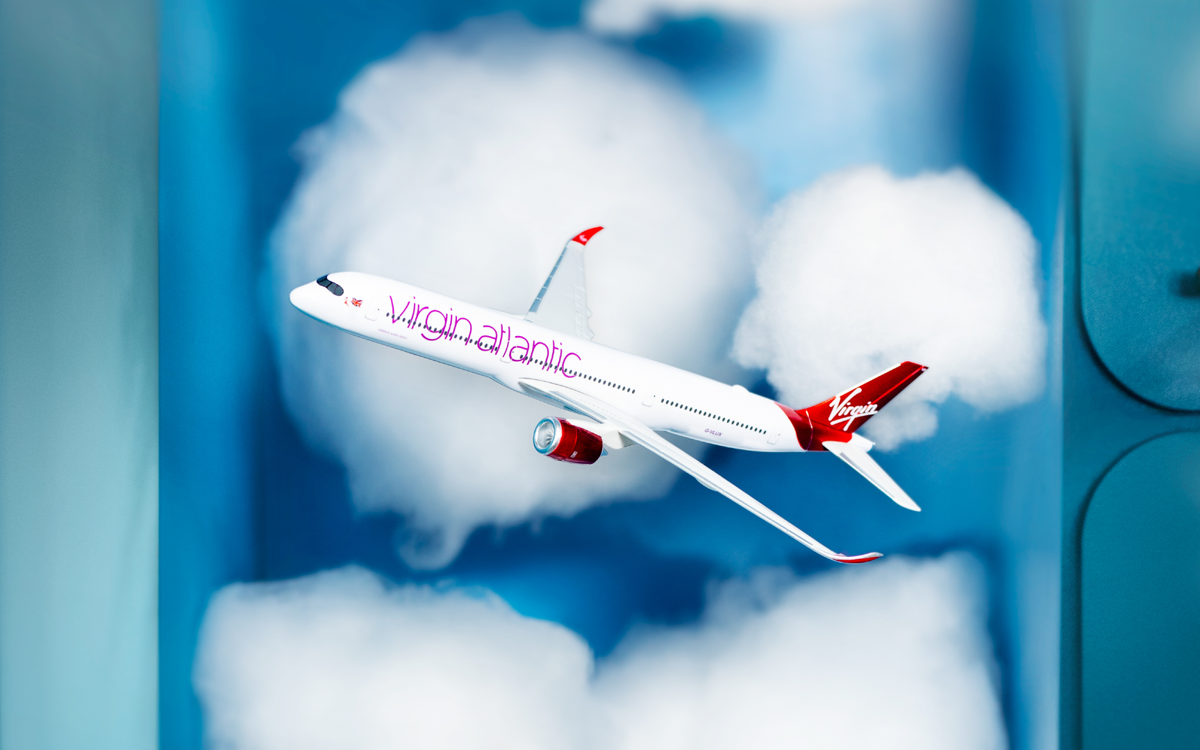 Image of a toy Virgin Atlantic aircraft flying through clouds.