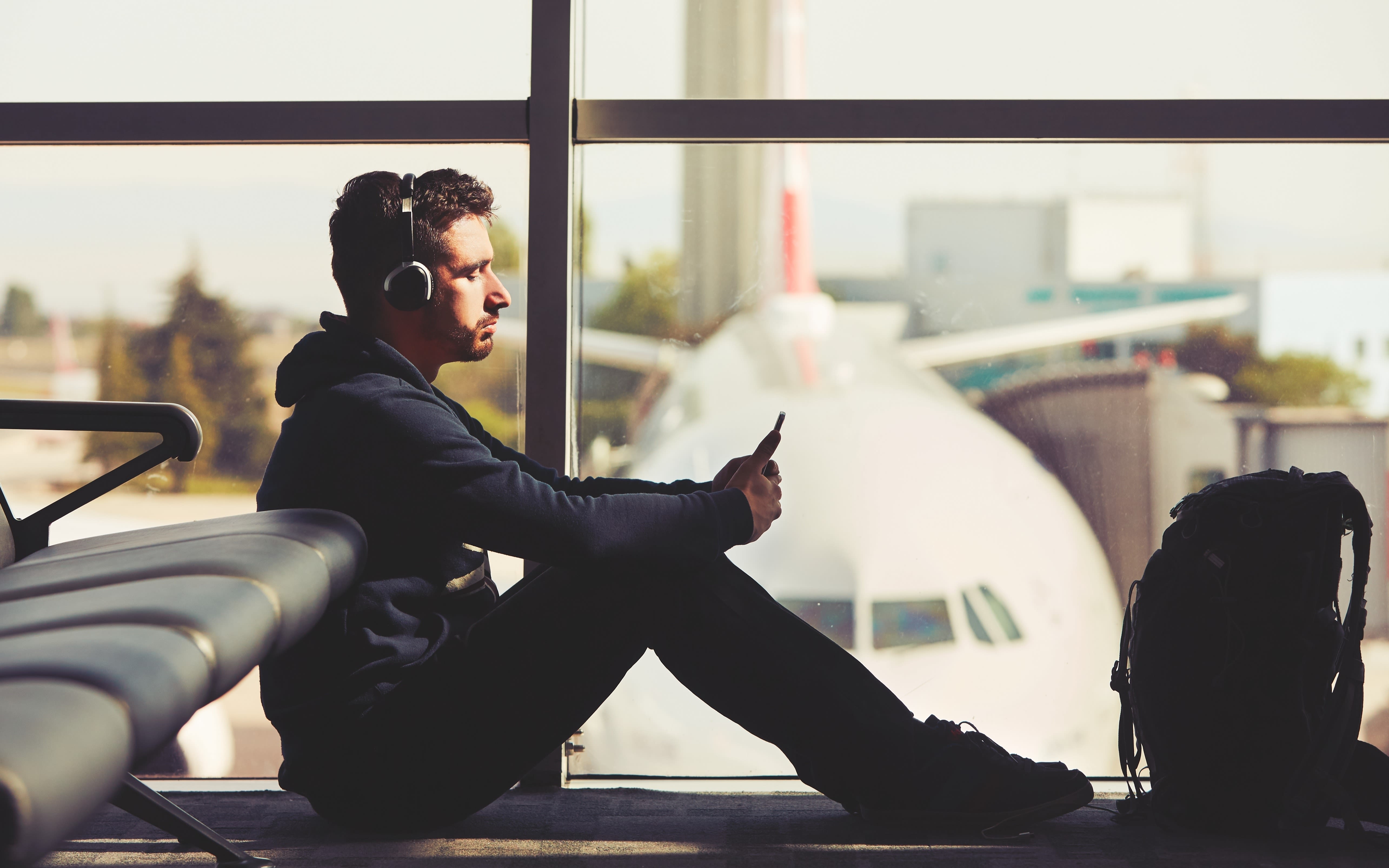 A young man listening to earphones at the airport. 