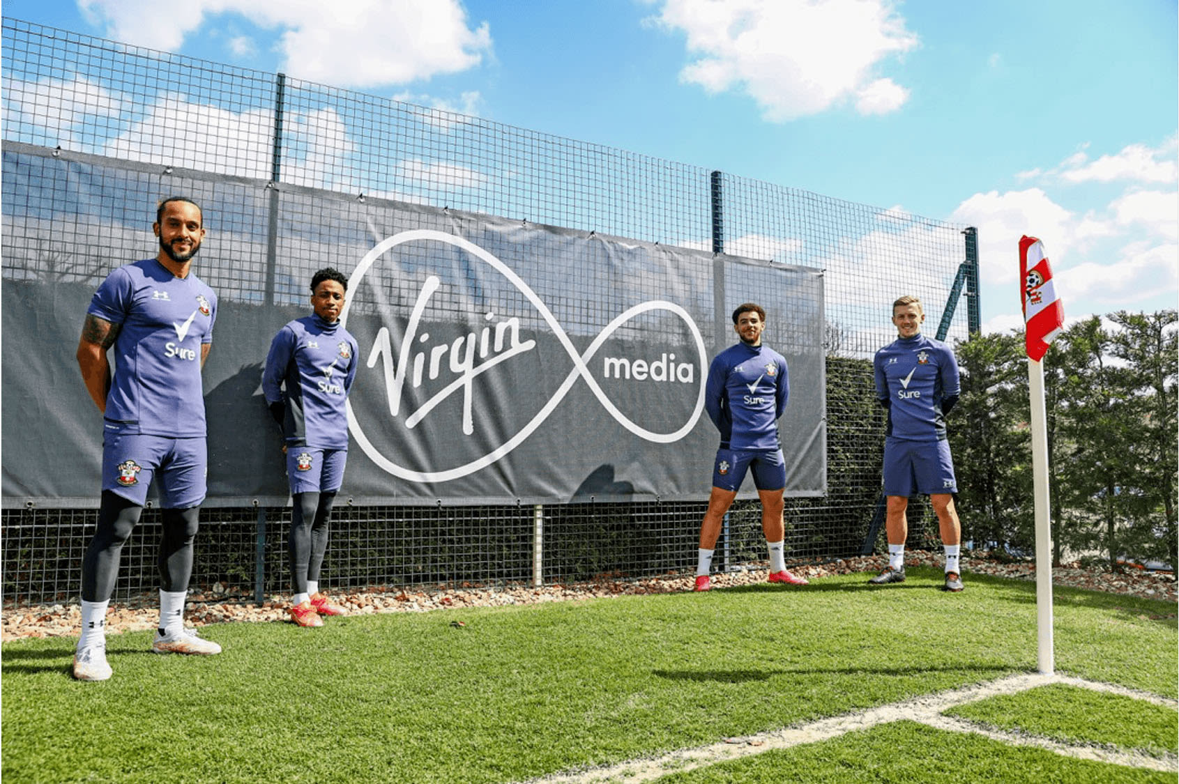 Southampton FC players stand next to a Virgin Media sign at the Staplewood training ground