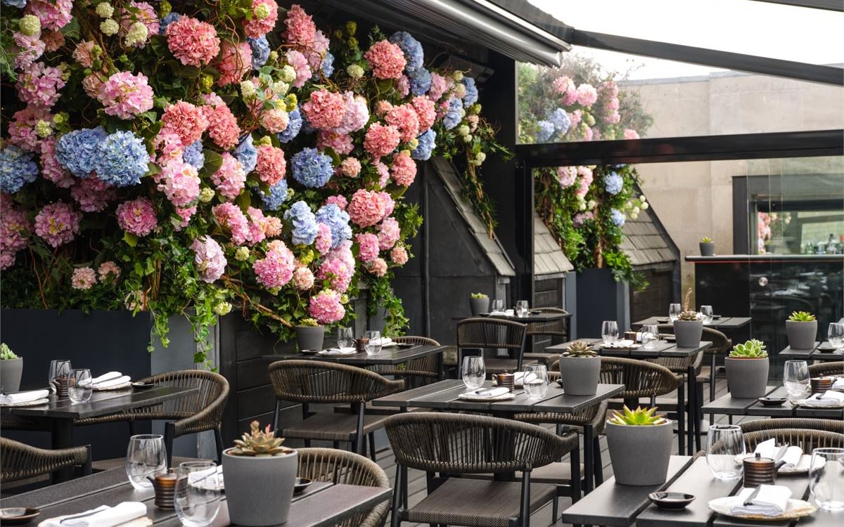 Image of the tables and flower wall at Aqua Koyoto restaurant and bar in London.