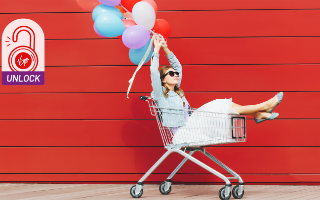 Image of a lady in a shopping trolley with balloons, very pleased about her purchases.