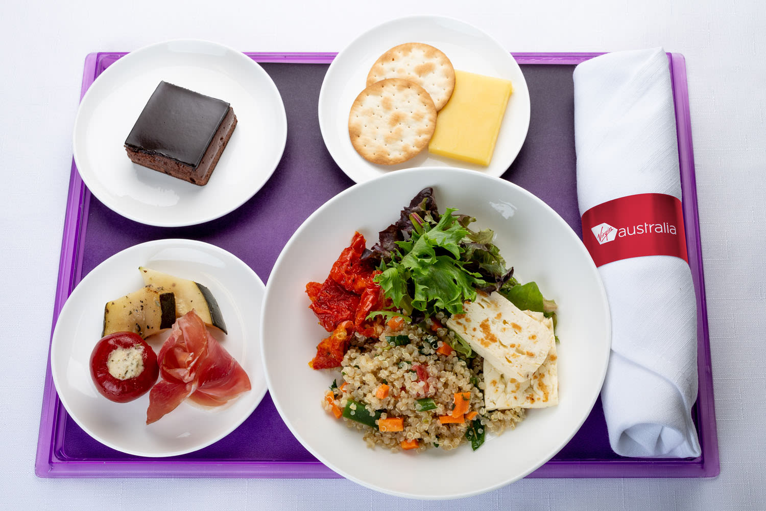 Haloumi and quinoa salad served alongside an antipasto plate with marinated vegetables, cheese and crackers and a chocolate delight cake Business Class offering Virgin Australia