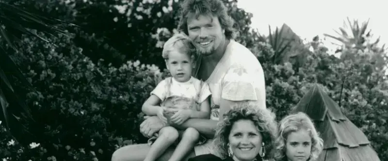 Black and white photo of Branson family. A young Sam Branson sits on Richard's knee. Joan and Holly sitting in front. 